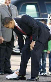 President Obama compares shoe size with shoe given to him from airport greeters in Phoenix. The shoe is autographed by Phoenix Suns basketball star Shaquille O'Neil.